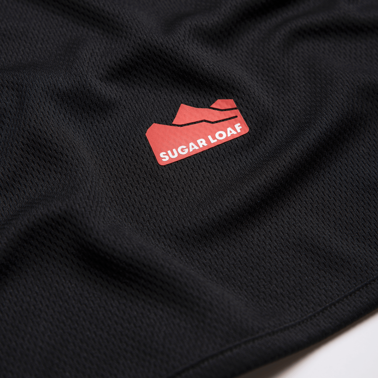 Flat lay of Sugar Loaf logo on black polyester shearing singlet - women's and men’s singlet vests built for hard work.