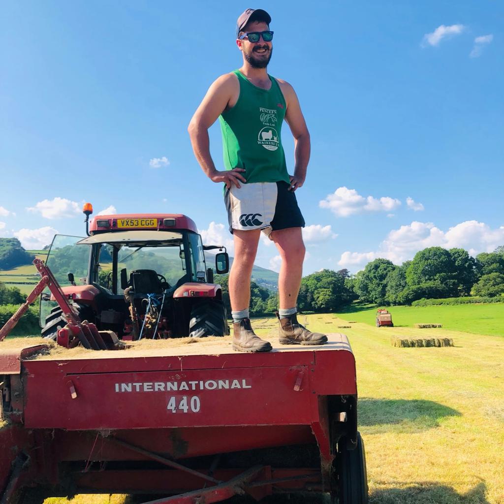 A man wearing white and black Canterbury shorts and posing on top of farm equipment