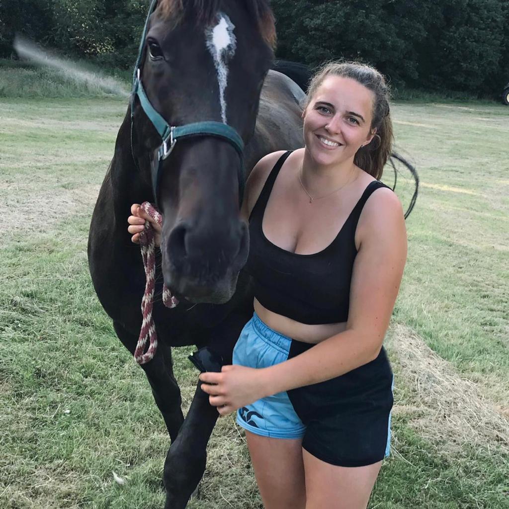 Woman leading horse and wearing canterbury clothing UK shorts