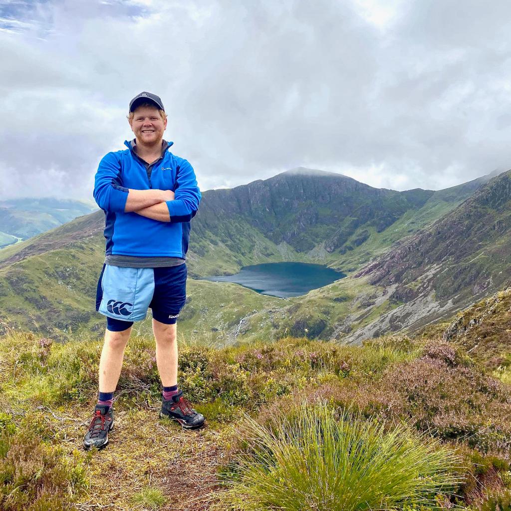 Hiker wearing rugby clothing and standing on a mountain range
