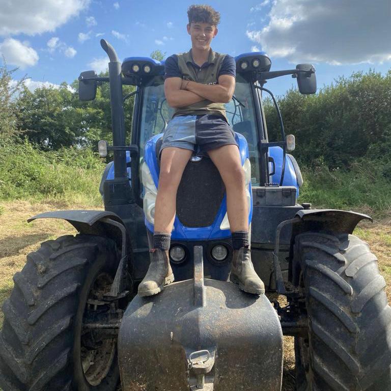 Young farmer wearing cronulla navy canterbury shorts and sitting on a tractor