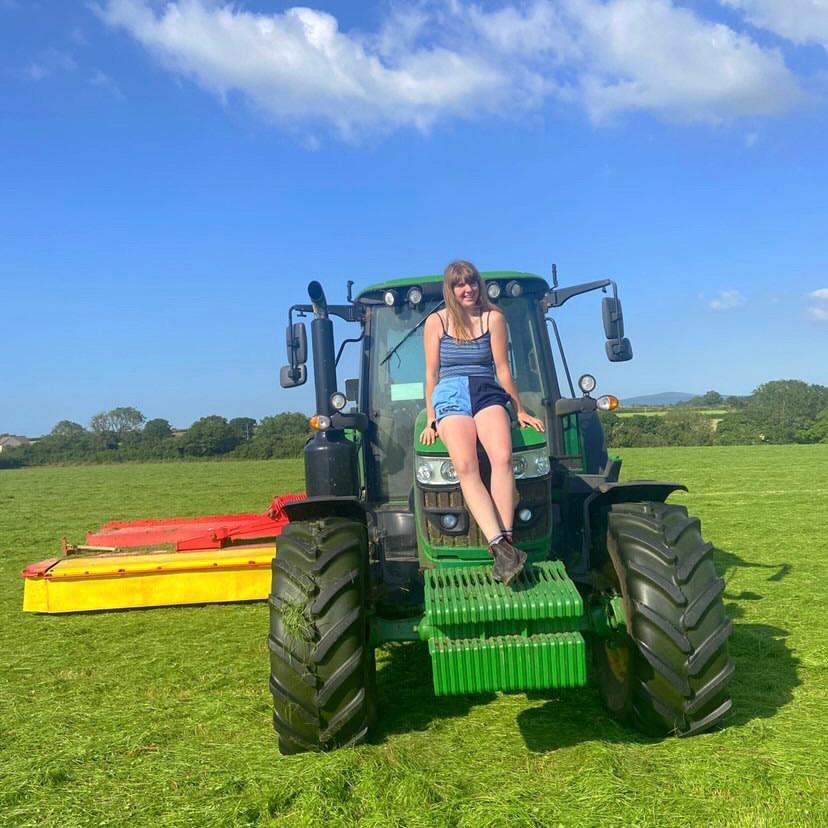 
                  
                    Woman wearing rugby clothing and siting on a farm vehicle
                  
                
