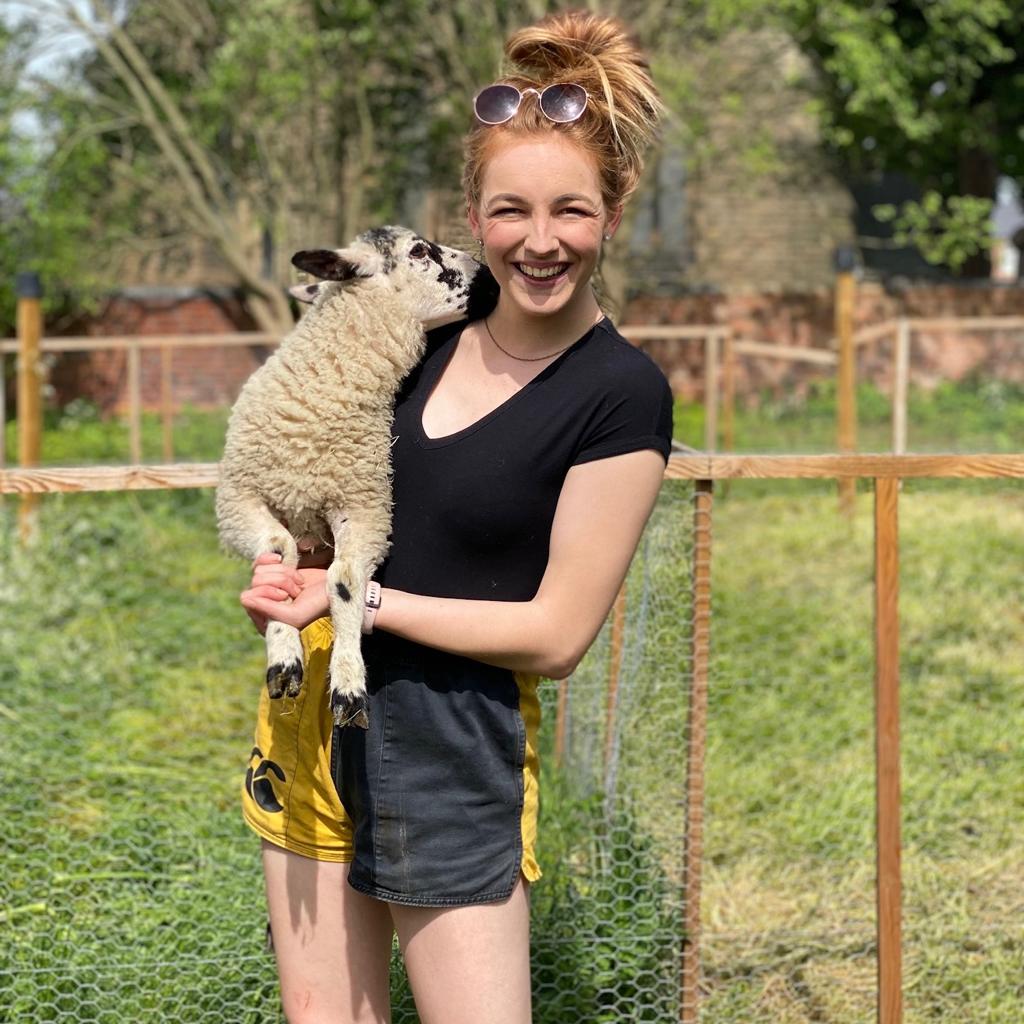 Woman wearing rugby shorts with pockets and holding a lamb