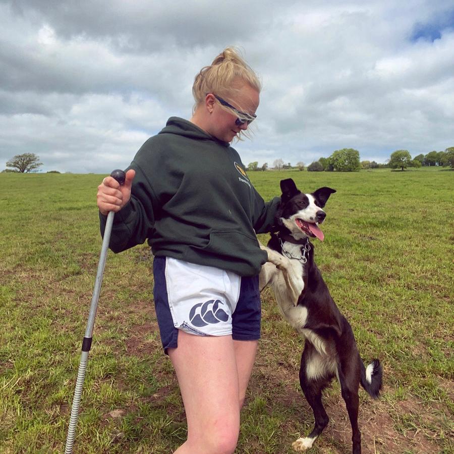 Hiker wearing white and navy Canterbury harlequin shorts and petting their dog