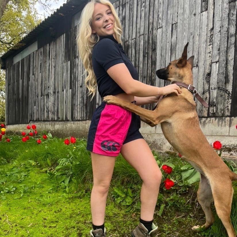 Pink and navy Canterbury shorts worn by a woman hugging her dog