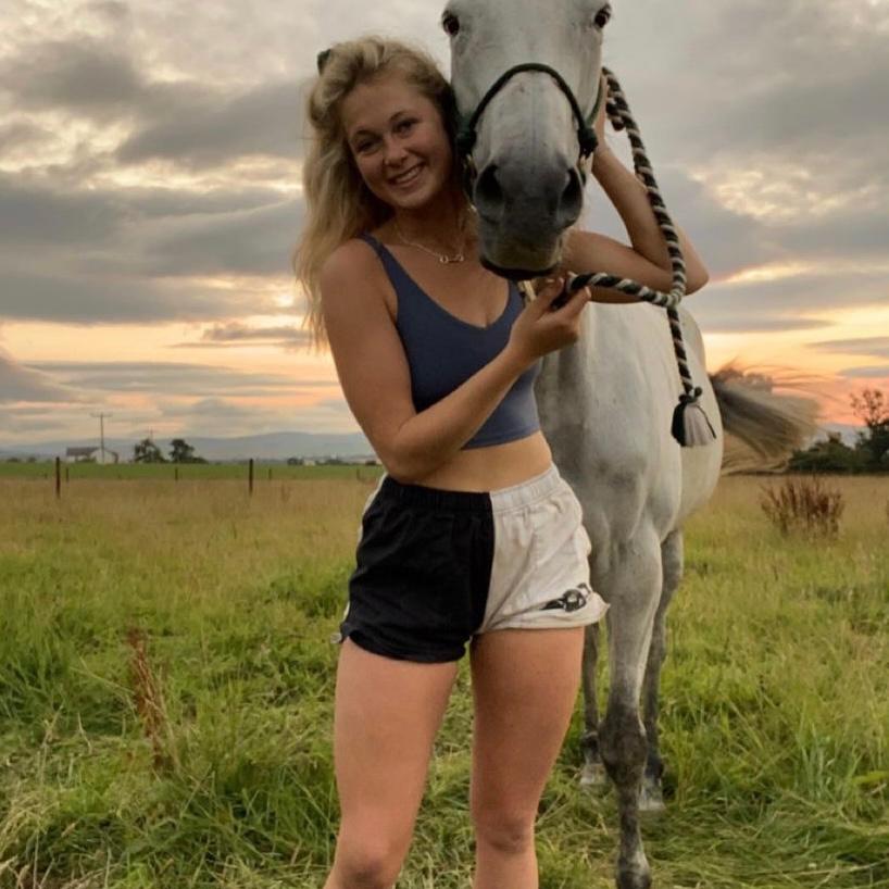 Woman wearing canterbury harlequin shorts and posing with a horse