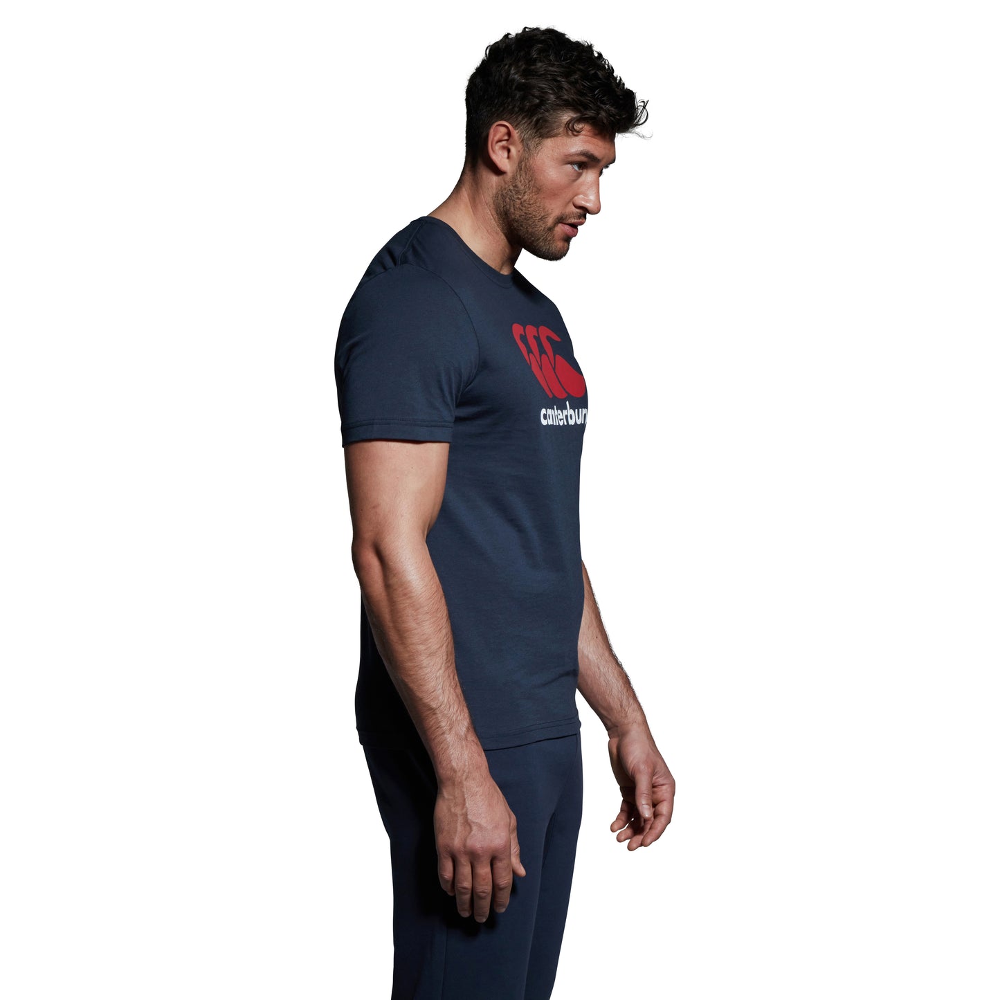 
                  
                    Dark haired man modelling navy Canterbury tshirts with red and white logo 
                  
                