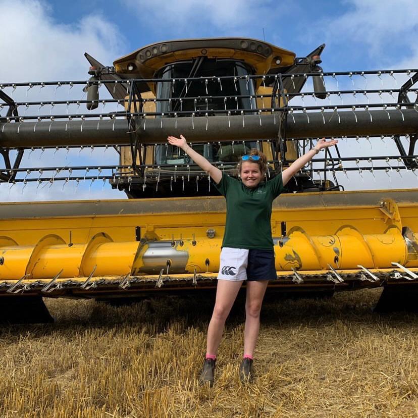 Farmer wearing white and navy Canterbury shorts in front of a combine harvester